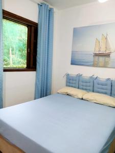 a bedroom with a bed and a painting of a sailboat at kit S1 condominio praia Bertioga - 600mt da praia in Bertioga