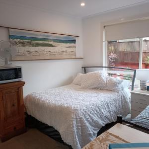 a bedroom with a bed and a painting on the wall at Byron Bay Nest Homestay in Byron Bay