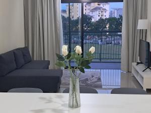 a vase with white roses on a table in a living room at Homestay Putrajaya Ayer 8 Elzahra Suites With Wi Fi in Putrajaya