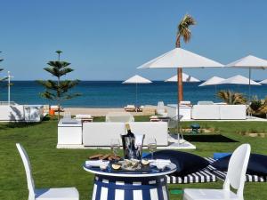 Una mesa con una botella de vino y sillas y la playa. en Sofitel Tamuda Bay Beach And Spa, en M'diq