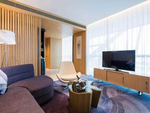 a living room with a couch and a flat screen tv at NOVOTEL Jinji Lake Suzhou SIP in Suzhou