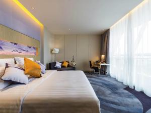 a hotel room with a large bed with yellow pillows at NOVOTEL Jinji Lake Suzhou SIP in Suzhou