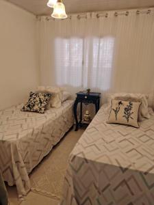 1 Schlafzimmer mit 2 Betten und einem Tisch mit einem Fenster in der Unterkunft Sítio das Águas in Santa Teresa
