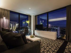 a living room with a couch and a large window at Pullman Sydney Airport in Sydney