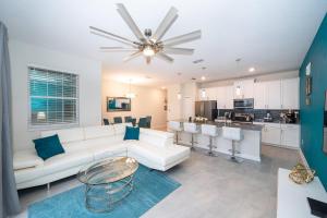 Una sala de estar con un sofá blanco y una cocina. en 4830FA TOWNHOUSE 4 BEDROOMS & 3 BATHROOMS + POOL, en Kissimmee