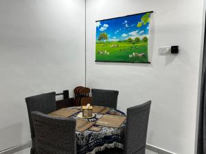 a dining room table with a painting on the wall at J&Y Homestay Kluang in Kluang