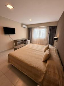 a bedroom with a large bed and a television at Hotel Alvarado Suites in Salta