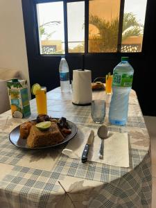 a table with a plate of food and a bottle of water at Villa serenité lac rose avec cuisinier ,piscine et jacuzzi terrasse vue lac in Ouayembame