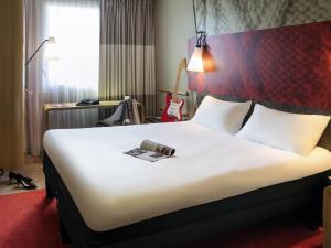 a hotel room with a bed with a book on it at ibis Saint Quentin en Yvelines - Vélodrome in Montigny-le-Bretonneux +85 photos