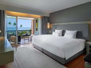 a bedroom with a large white bed and a balcony at Pullman Phuket Panwa Beach Resort in Panwa Beach