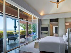 a bedroom with a bed and a balcony with a table at Pullman Phuket Panwa Beach Resort in Panwa Beach