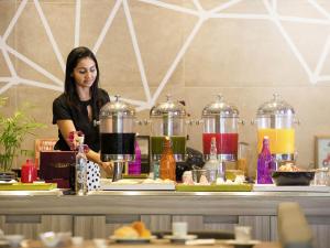 a woman standing behind a counter with some food at Novotel RJ Porto Atlantico in Rio de Janeiro