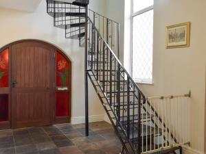 a spiral staircase in a hallway next to a door at Green Acre Cottage in Kilgetty +12 photos