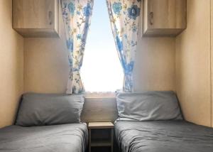 zwei Betten in einem kleinen Zimmer mit Fenster in der Unterkunft Towervans Caravan Park in Mablethorpe