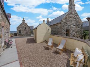 a patio with two chairs and a building at Coast Away in Fraserburgh