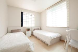 two beds in a bedroom with white walls and a window at Kinpark Stay 