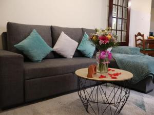 un soggiorno con divano e tavolo con vaso di fiori di Charming Retreat Machico - 5 min Praia & Centro B a Machico