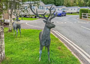 two deer statues standing in the grass near a street at Lemonford Caravan Park in Bickington
