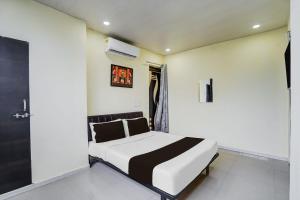 a bedroom with a white and black bed and a window at HOTEL O REGAL INN in Dhantoli