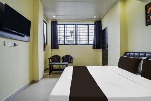 a bedroom with a bed and chairs and a tv at HOTEL O REGAL INN in Dhantoli