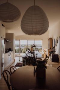 a living room with a table and a kitchen with windows at Seafarers Lodge a pup friendly beach shack haven in Middleton in Middleton +33 photos