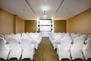 a conference room with white chairs and a screen at Harper Perintis by ASTON in Makassar
