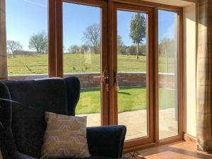 a room with sliding glass doors with a view of a field at Chick Hatch Barn in Kelsale