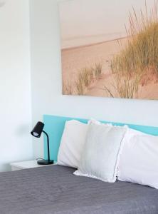 a bed with white pillows and a picture of the beach at Robetown Motor Inn & Apartments in Robe