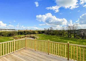 una terraza de madera con una valla y un campo en Holderness Country Park, en Tunstall