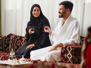 a man and woman sitting on a couch drinking wine at ibis Styles Makkah in Makkah