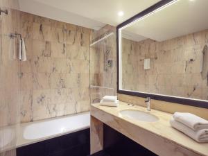 a bathroom with a sink and a tub and a mirror at Mercure Paris Saint-Ouen in Saint-Ouen +78 photos