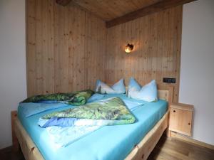 a bedroom with a bed with blue sheets and pillows at Rustic cabin with sauna near the ski area in Pankrazberg