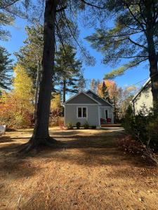a white house with a tree in the yard at Serene Getaway Nordic Spa , Sauna, Nature & Pool in Rawdon