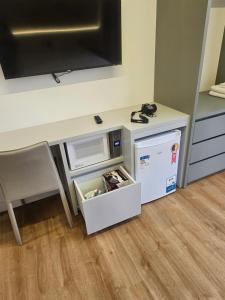 a room with a desk with a microwave and a table with a chair at Suite privada en Four Seasons Residence monoambiente in Bombinhas
