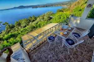 a table and chairs on a balcony with a view of a lake at Villa Pergola in Pyrgi