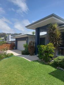 a house with a garage and a grass yard at Stones Throw at Sapphire in Coffs Harbour