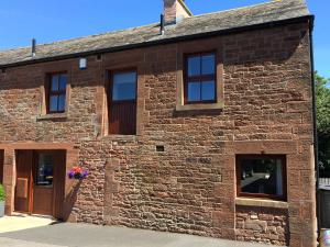 ein altes Backsteingebäude mit Fenstern und Blumen in einem Fensterkasten in der Unterkunft The Old Bothy in Wigton