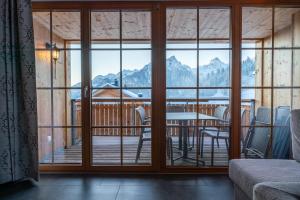a room with a balcony with a table and chairs at Landal Brandnertal in Bürserberg
