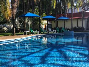 San Juan Bautista TuxtepecにあるHotel Campestre Santa Claraの青いパラソルと椅子付きのスイミングプール +11枚の写真