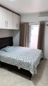a bedroom with a large bed in front of a window at Espaço da Char in Praia Grande