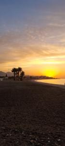 una puesta de sol en una playa con palmeras y el océano en Nerja Rio marinas Playa, Garden with Pool, en Nerja 35 fotos más