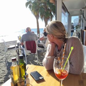 a woman sitting at a table near the beach at Nerja Rio marinas Playa, Garden with Pool in Nerja +42 photos