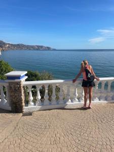a woman standing on a balcony looking at the water at Nerja Rio marinas Playa, Garden with Pool in Nerja