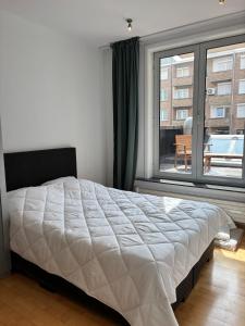 een slaapkamer met een bed en een groot raam bij Spacious and comfortable apartment in Knokke-Heist