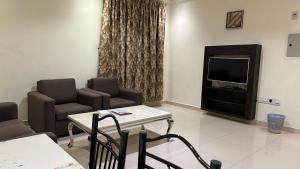 Una sala de estar con una mesa y sillas y un televisor. en سلس للشقق المخدومة - فرع الرفيعة, en Riad