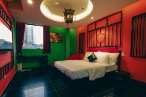 a red and green bedroom with a bed and a chandelier at Love in the Atlantis Hotel in Hanoi