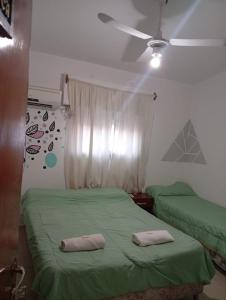 a bedroom with two green beds and a ceiling fan at Hotel inti huasi in Villa Carlos Paz