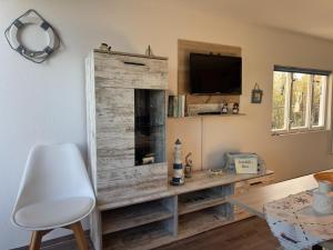 a living room with a wooden entertainment center with a tv at Bootshaus direkt am See in Sternberg