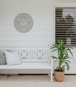 a white house with a bench and a plant at White Haven Port Willunga 6 Bedroom group entertainer with Games shed and Pizza oven in Port Willunga
