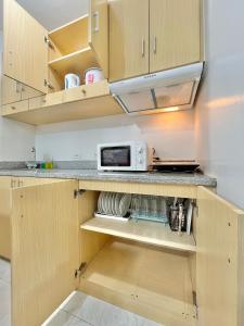 a kitchen with wooden cabinets and a microwave at 2 Bedroom Condo Fully-Furnished good for 5-6pax by Gerra at Urban Deca Homes Banilad in Mandaue City
